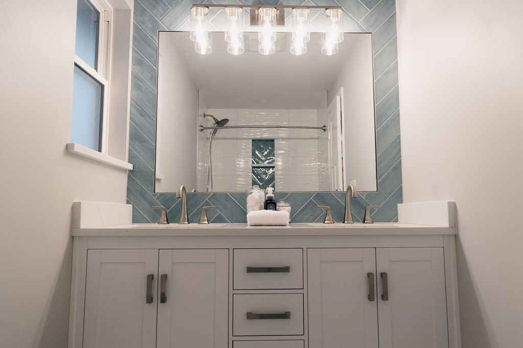 White vanity and luxury chandelier for a guest bathroom remodel project in Auburn